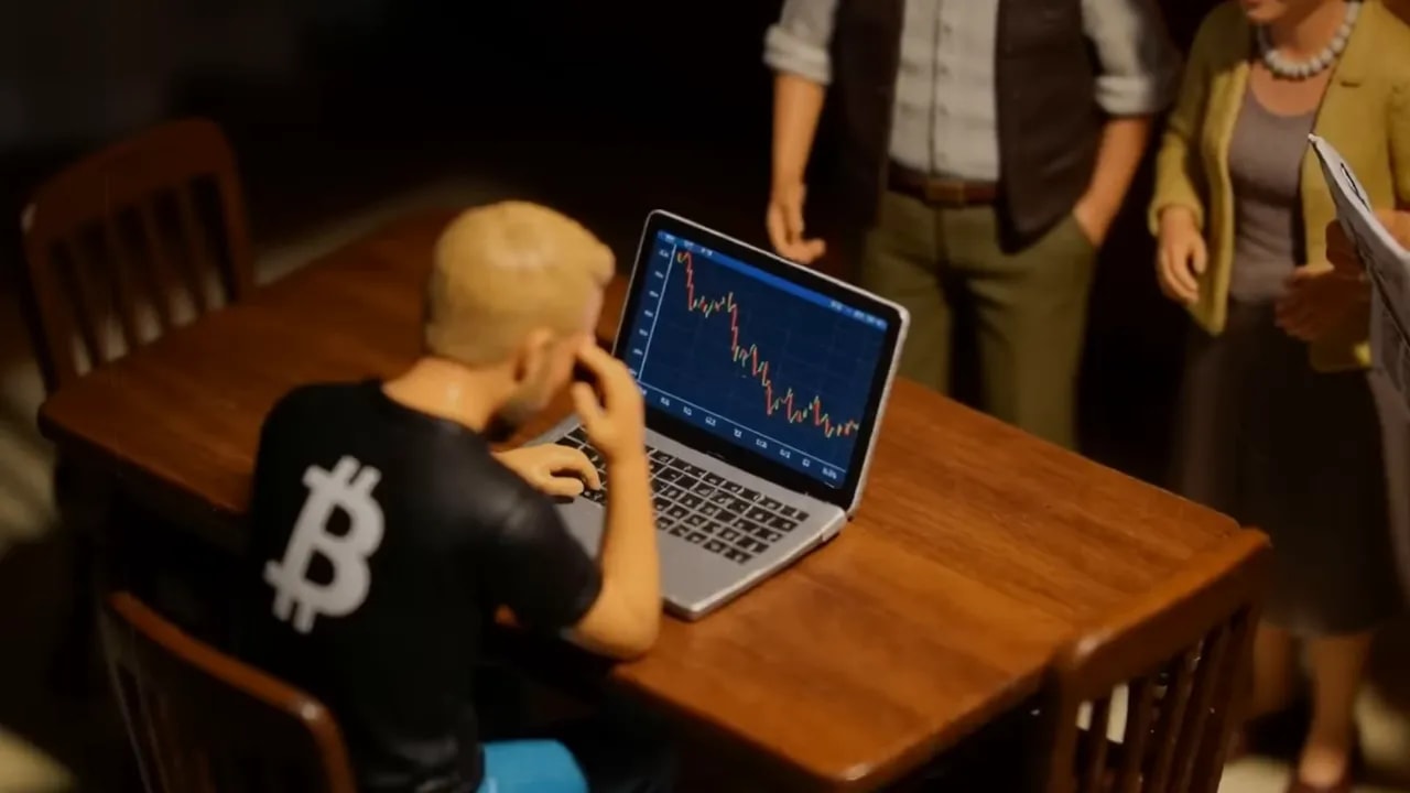 Person sitzt vor Laptop mit fallendem Kursdiagramm an einem Tisch